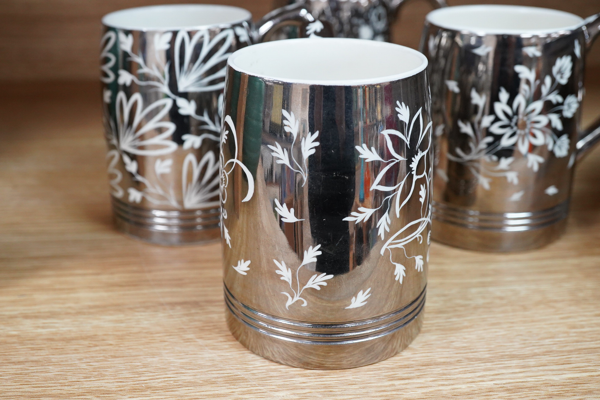 Keith Murray for Wedgwood, a set of four silvered mugs, decorated by Millicent Taplin, largest 10cm high